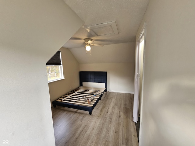 bedroom with light hardwood / wood-style flooring, vaulted ceiling, and ceiling fan