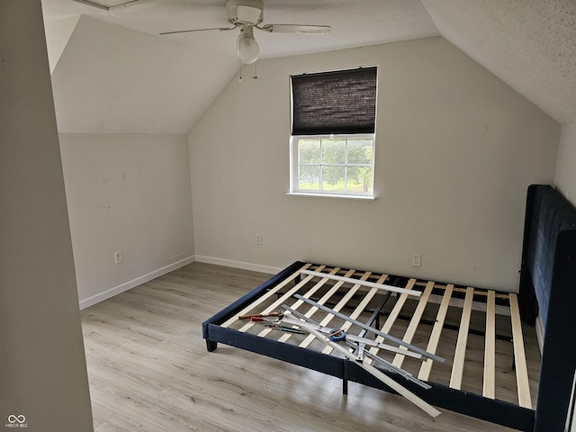 unfurnished bedroom featuring vaulted ceiling, ceiling fan, light hardwood / wood-style floors, and a textured ceiling