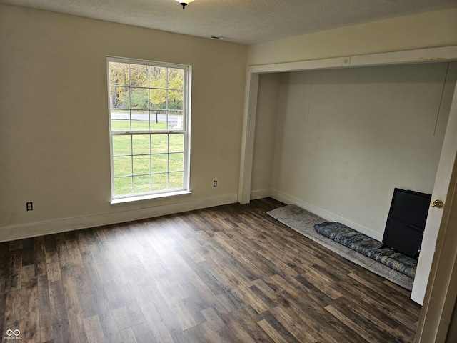 unfurnished bedroom with a textured ceiling, dark hardwood / wood-style floors, and a closet