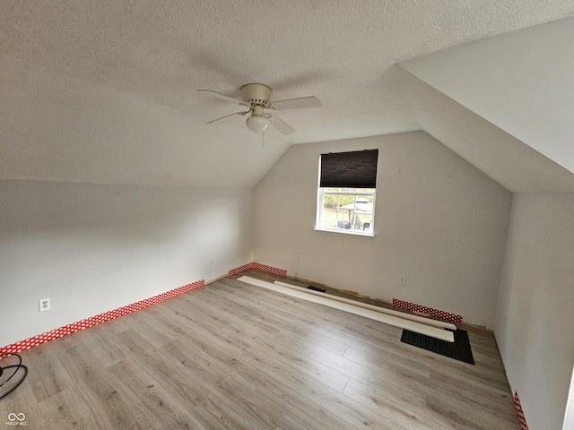 additional living space with a textured ceiling, light hardwood / wood-style flooring, and lofted ceiling