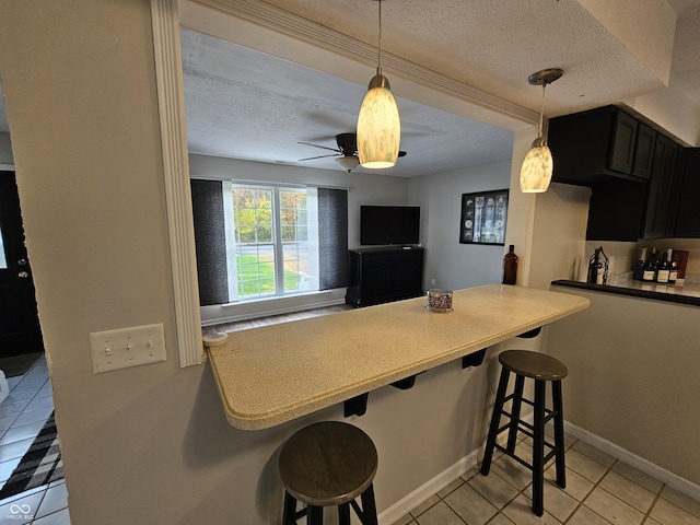 kitchen featuring ceiling fan, hanging light fixtures, a breakfast bar area, and light tile patterned flooring