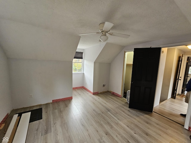 bonus room featuring a textured ceiling, light wood-type flooring, ceiling fan, and lofted ceiling