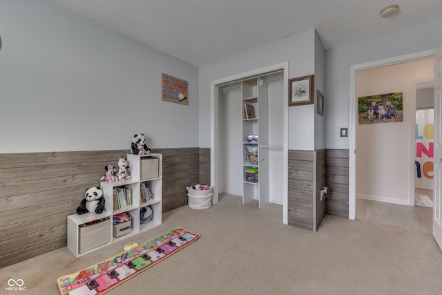 rec room with a textured ceiling and light carpet