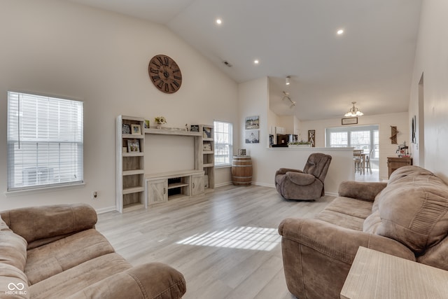 living room with light hardwood / wood-style floors, high vaulted ceiling, and a chandelier