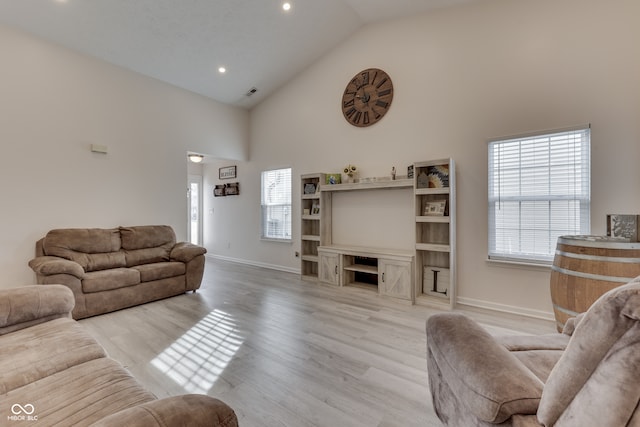 living room featuring high vaulted ceiling and light hardwood / wood-style flooring