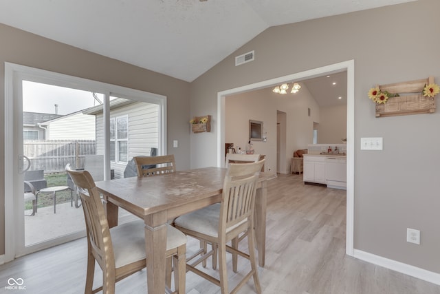 dining area featuring lofted ceiling, plenty of natural light, a chandelier, and light hardwood / wood-style flooring