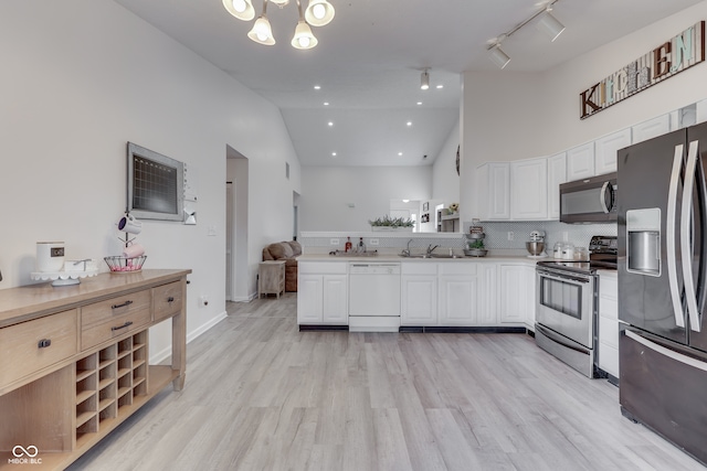 kitchen with appliances with stainless steel finishes, high vaulted ceiling, and white cabinetry