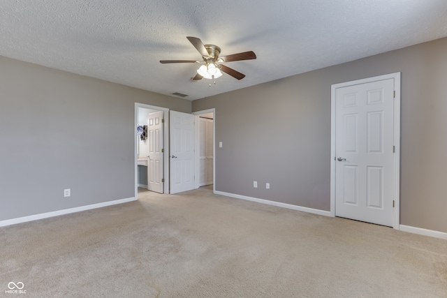 unfurnished bedroom with light carpet, ensuite bathroom, a textured ceiling, and ceiling fan