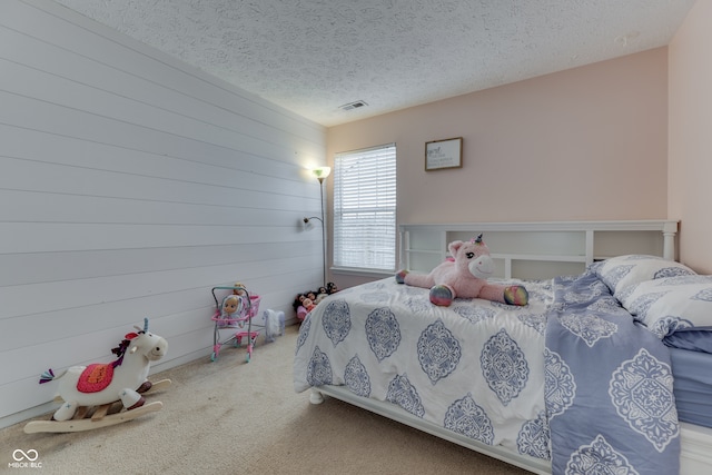 carpeted bedroom with a textured ceiling and wood walls