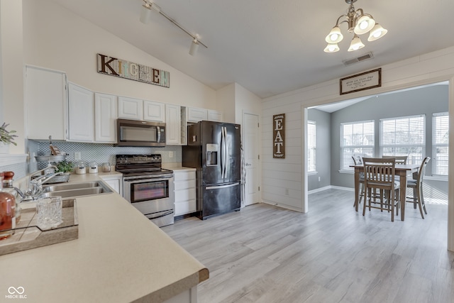 kitchen featuring light wood-type flooring, vaulted ceiling, sink, stainless steel appliances, and white cabinetry