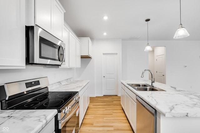 kitchen with white cabinets, a center island with sink, hanging light fixtures, sink, and stainless steel appliances