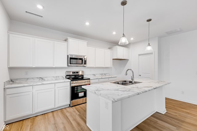 kitchen with stainless steel appliances, white cabinetry, a kitchen island with sink, and sink