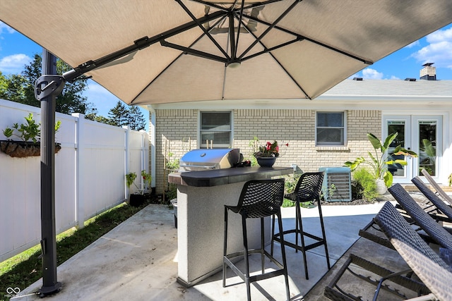 view of patio / terrace with french doors, area for grilling, and a bar