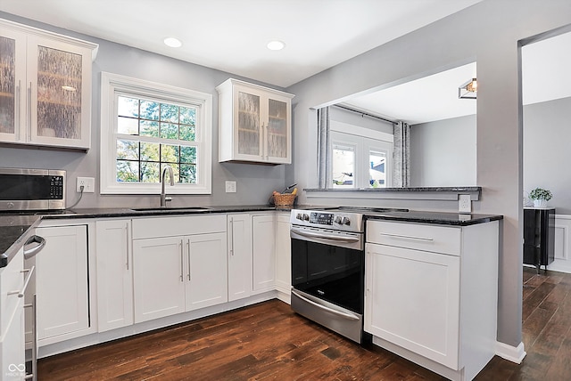 kitchen with sink, white cabinetry, appliances with stainless steel finishes, dark stone counters, and dark hardwood / wood-style flooring