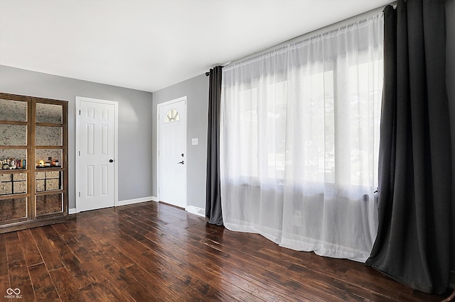 empty room with plenty of natural light and dark hardwood / wood-style flooring