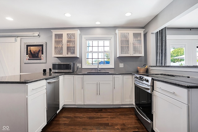 kitchen featuring stainless steel appliances, kitchen peninsula, sink, and white cabinetry