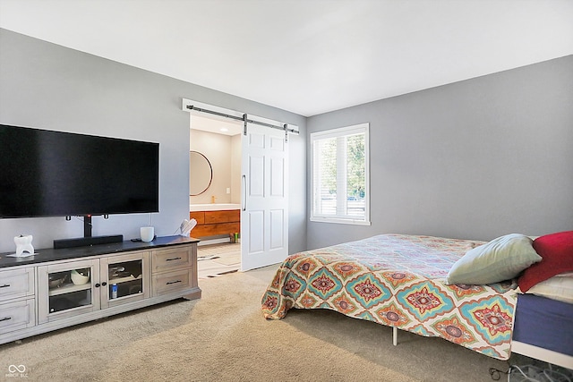 bedroom featuring ensuite bath, a barn door, and light colored carpet