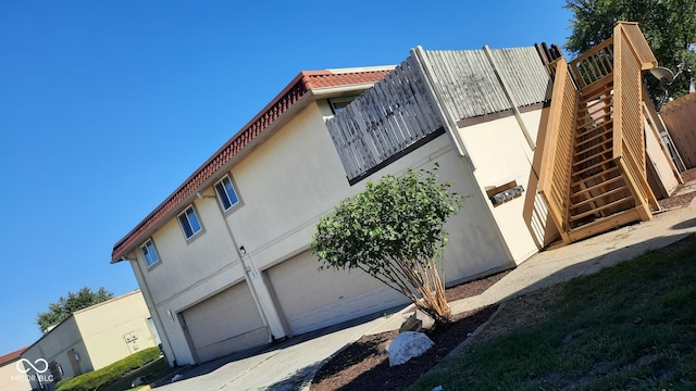 view of property exterior featuring a garage and a wooden deck