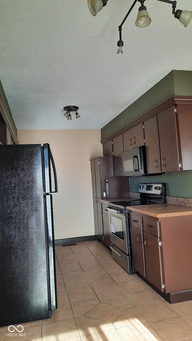 kitchen with light tile patterned flooring, dark brown cabinetry, stainless steel appliances, and a textured ceiling