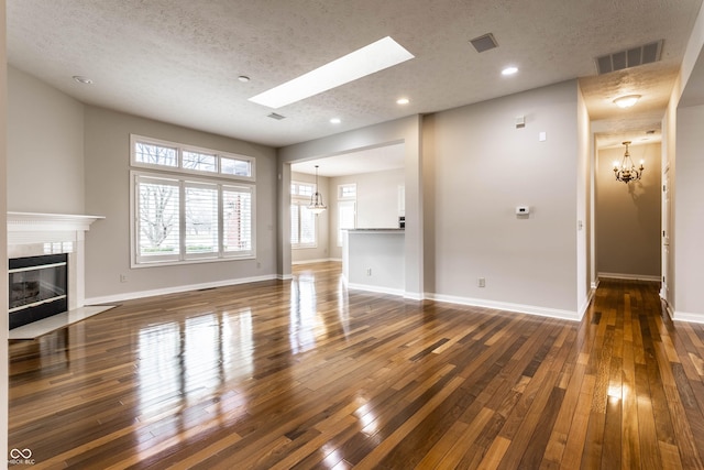 unfurnished living room with a tiled fireplace, dark hardwood / wood-style floors, and a textured ceiling