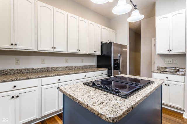 kitchen featuring white cabinetry, a kitchen island, pendant lighting, and stainless steel fridge