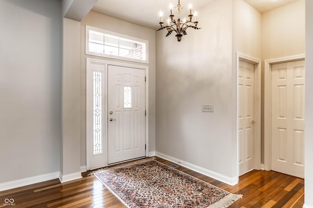 foyer entrance with an inviting chandelier, a towering ceiling, and dark hardwood / wood-style flooring