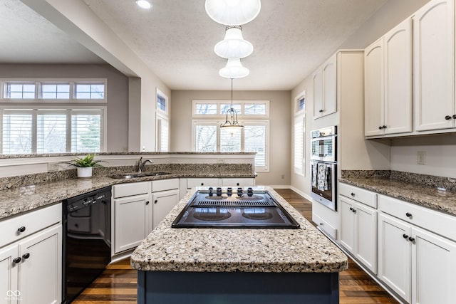 kitchen featuring hanging light fixtures, a center island, sink, and black appliances