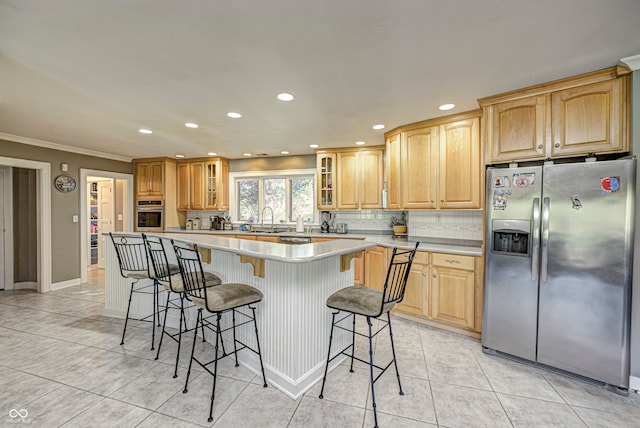 kitchen with decorative backsplash, glass insert cabinets, a breakfast bar area, stainless steel appliances, and a sink