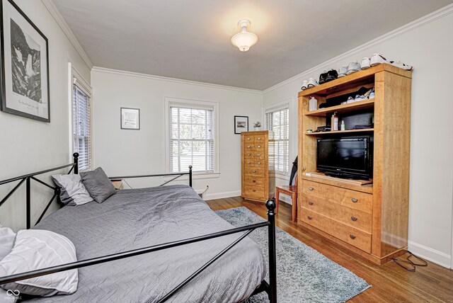 bedroom with baseboards, ornamental molding, and wood finished floors