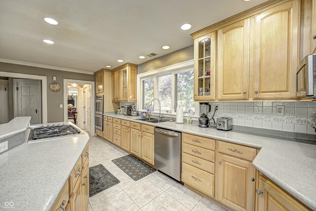 kitchen with stainless steel appliances, tasteful backsplash, light brown cabinetry, glass insert cabinets, and a sink