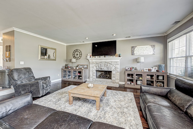 living area with visible vents, crown molding, a stone fireplace, and wood finished floors