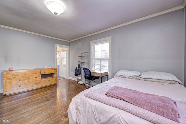 bedroom featuring baseboards, wood finished floors, and crown molding