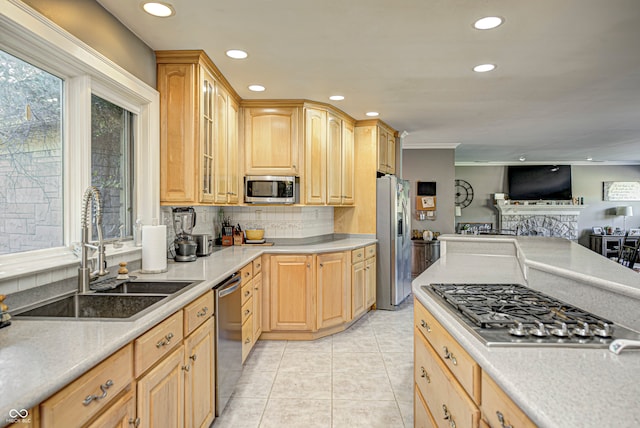 kitchen with stainless steel appliances, light brown cabinetry, a sink, and glass insert cabinets