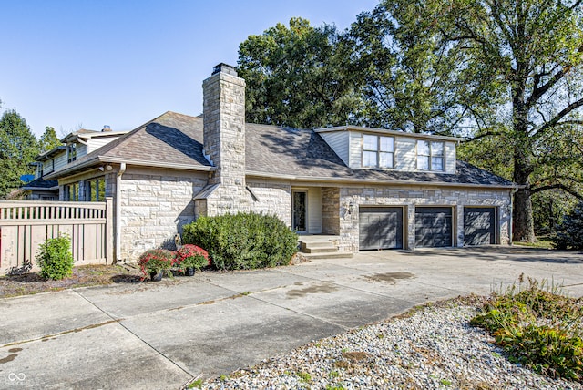 view of front facade featuring a chimney, fence, a garage, stone siding, and driveway