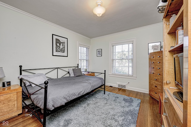 bedroom with baseboards, visible vents, ornamental molding, and wood finished floors