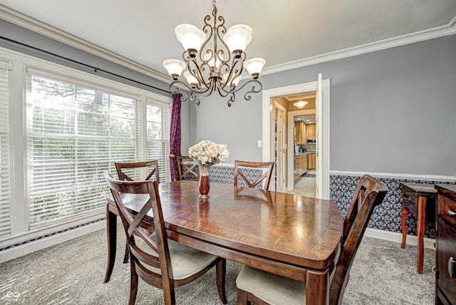 dining area featuring wainscoting, light colored carpet, crown molding, and an inviting chandelier