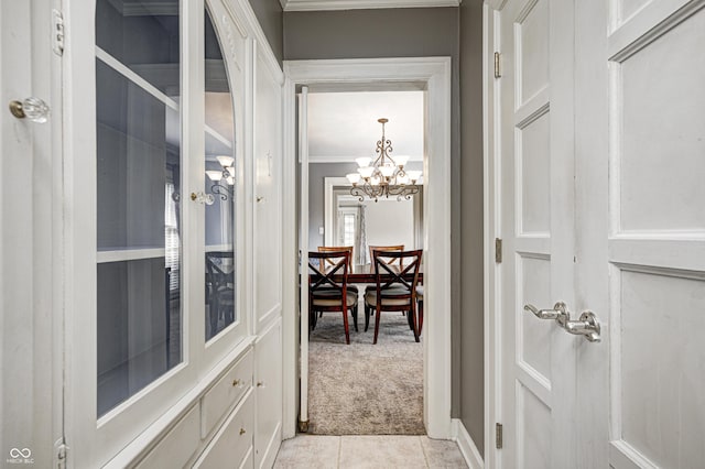 entryway featuring light carpet, light tile patterned floors, ornamental molding, and a notable chandelier