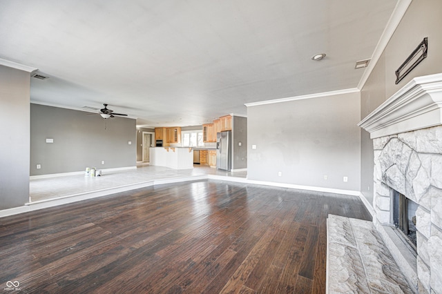 unfurnished living room with ornamental molding, light wood-type flooring, a stone fireplace, and baseboards