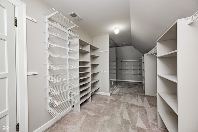 walk in closet featuring carpet, visible vents, and vaulted ceiling