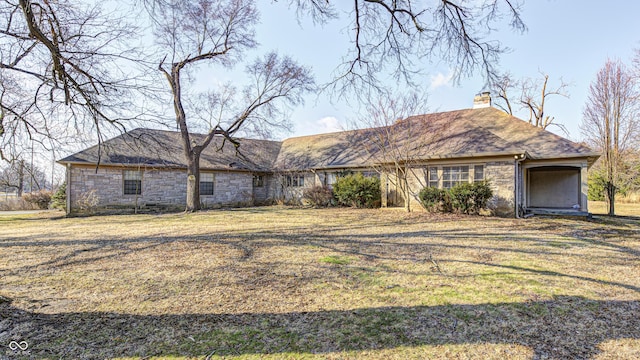 single story home featuring stone siding, a front lawn, and a chimney