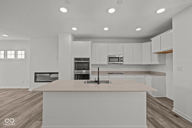 kitchen featuring white cabinetry, sink, an island with sink, and stainless steel appliances