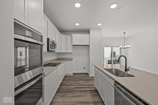 kitchen featuring stainless steel appliances, dark wood-type flooring, sink, decorative light fixtures, and white cabinetry