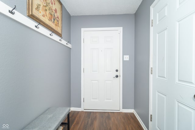 doorway to outside with a textured ceiling and dark wood-type flooring