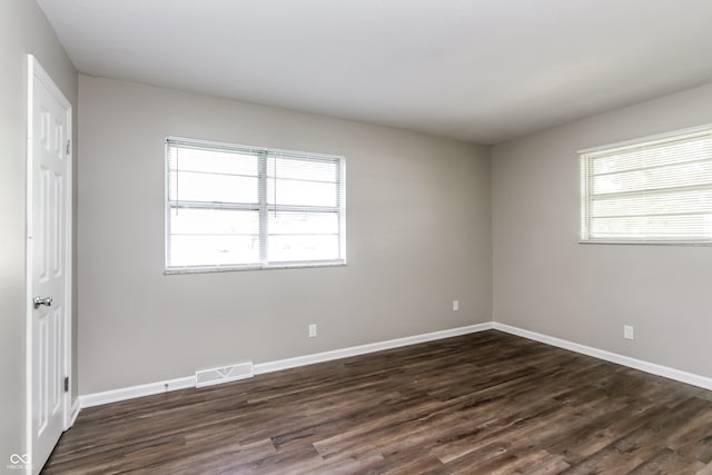 empty room with dark hardwood / wood-style flooring and a healthy amount of sunlight