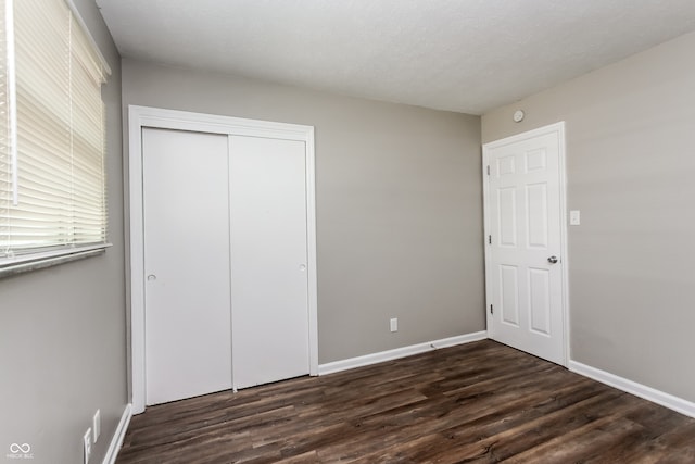 unfurnished bedroom with dark wood-type flooring, a closet, and a textured ceiling