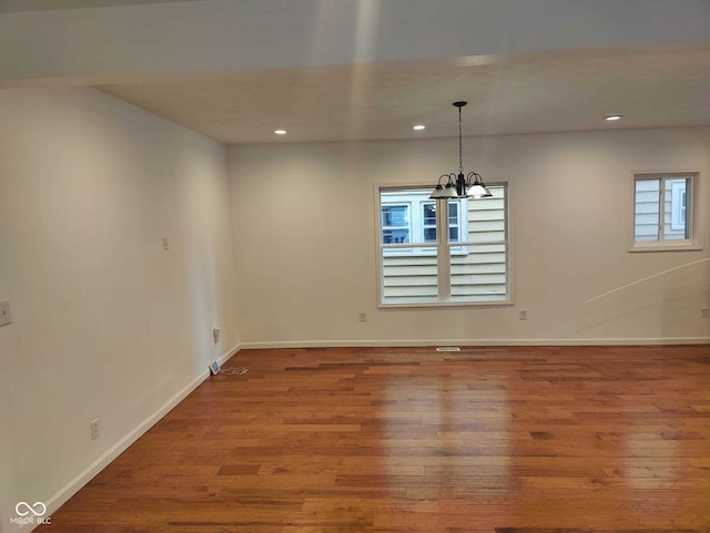 unfurnished dining area featuring an inviting chandelier, plenty of natural light, and hardwood / wood-style floors