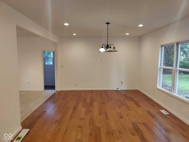 unfurnished dining area featuring a chandelier and wood-type flooring