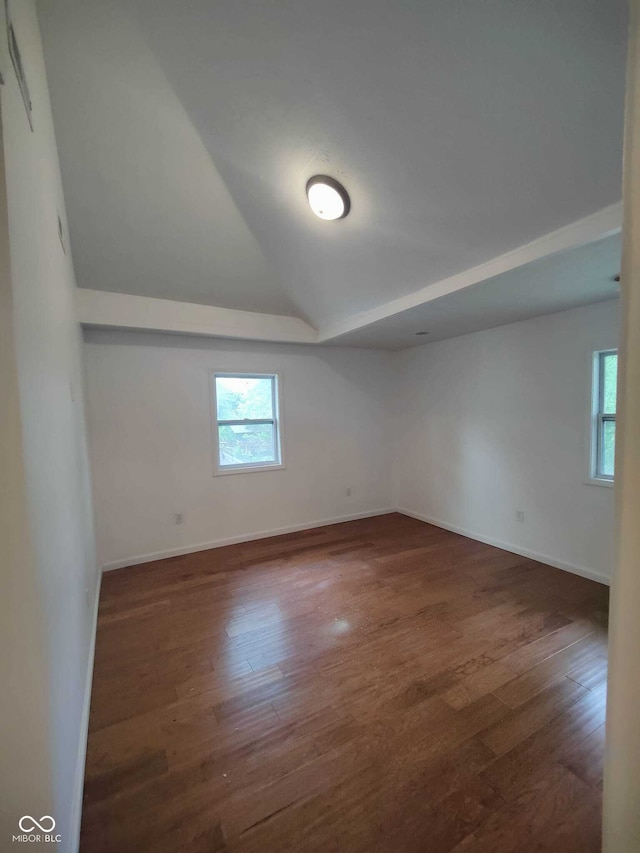 spare room featuring vaulted ceiling and dark hardwood / wood-style flooring