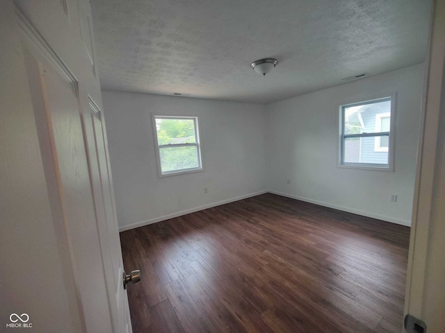 empty room featuring a textured ceiling and dark hardwood / wood-style flooring