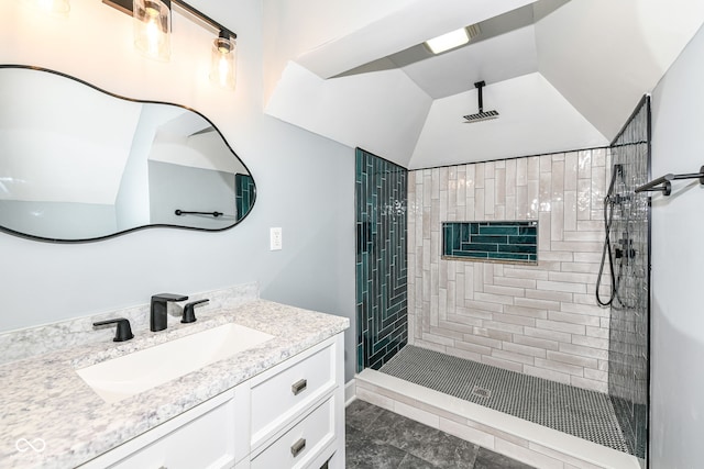 bathroom featuring lofted ceiling, tiled shower, and vanity